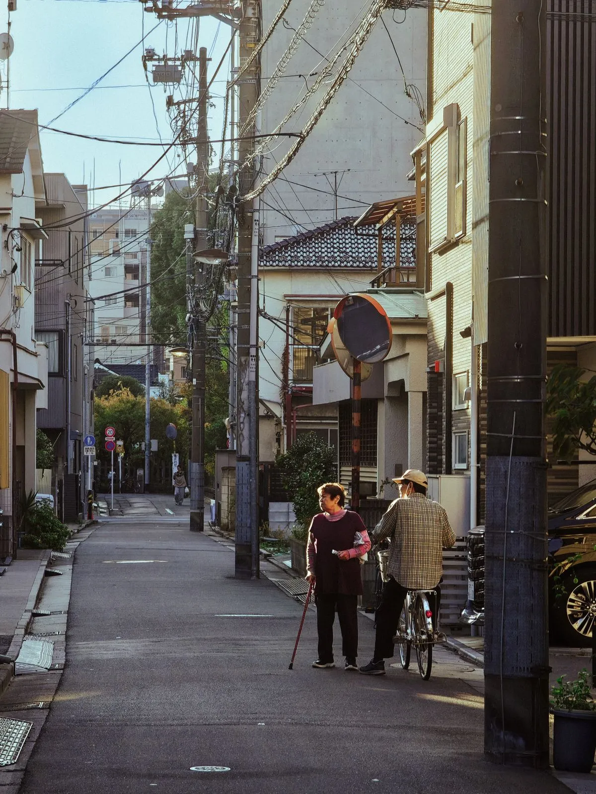 夕方の住宅街の路地で立ち話をする年配のふたり